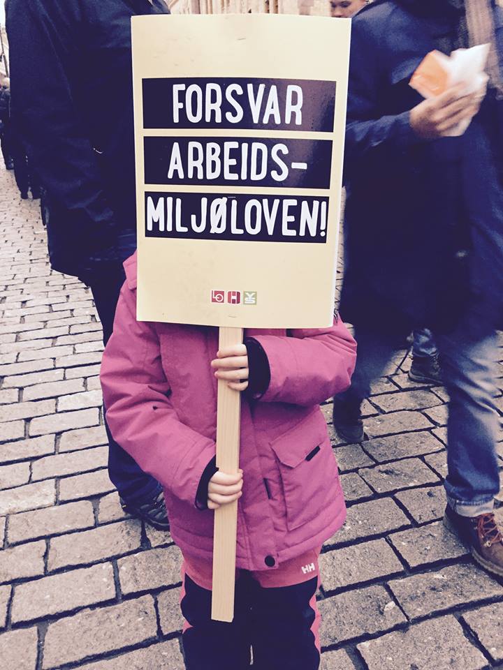 Bilde av jente som holder skilt med forsvar arbeidsmiljøloven